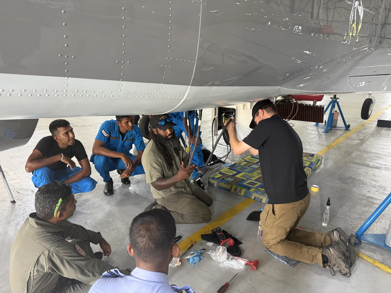 Technicians receiving hands-on instruction beneath a King Air in a hangar